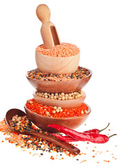 Stack bowls of different lentils and soy beans with red hot peppers isolated on a white background.