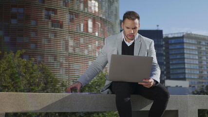 Businessman having video chat on laptop at street. Freelancer using computer