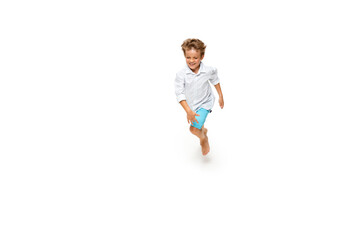 Happy child, little and emotional caucasian boy jumping and running isolated on white background. Looks happy, cheerful, sincere. Copyspace for ad. Childhood, education, happiness concept.