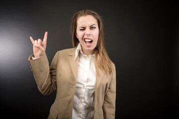 ragazza bionda con giacca beige fa il segno delle corna dopo repper, isolata su sfondo nero
