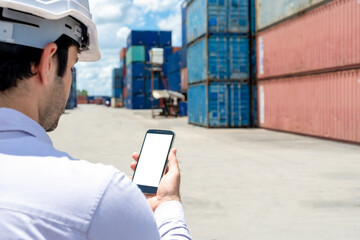 Close up back view of engineer or business man using blank white screen mobile phone in containers shipyard background. Business Cargo Ship Import/Export Factory Logistic.
