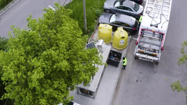 Aerial shot of garbage men with trash truck picking up the city garbage. Waste disposal
