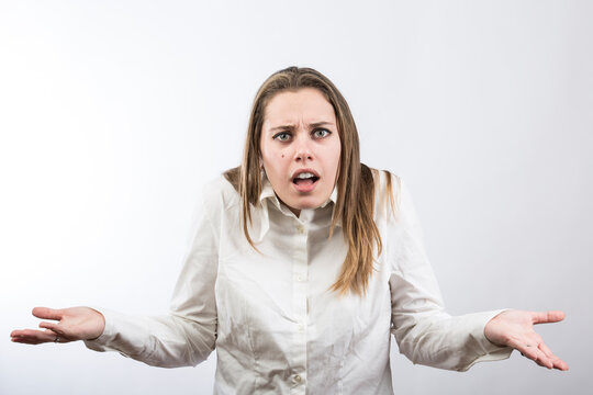 ragazza bionda con camicia bianca fa delle smorfie per dimostrare stupore assoluto, isolata su sfondo bianco