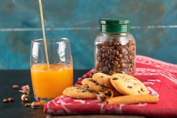 Cookies with chocolate drops served with a glass of orange juice