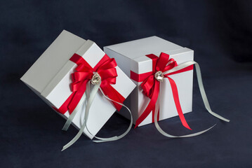 The gift box is white with a beautiful red bow. Gift on a dark background. Holidays and surprises....