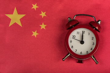 China flag and vintage alarm clock close up. Time to travel in China