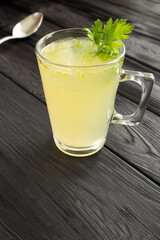 Chicken broth in the glass on the black wooden background. Location vertical.