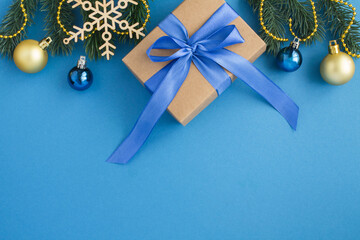 Christmas composition and gift with blue bow on the blue background. Top view. Copy space.
