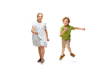 Happy children, little and emotional caucasian girl and boy jumping and running isolated on white background. Looks happy, cheerful, sincere. Copyspace for ad. Childhood, education, happiness concept.