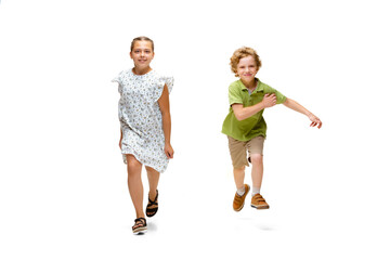 Happy children, little and emotional caucasian girl and boy jumping and running isolated on white background. Looks happy, cheerful, sincere. Copyspace for ad. Childhood, education, happiness concept.