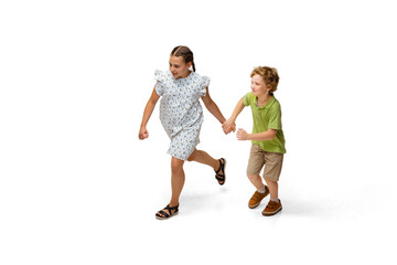 Happy children, little and emotional caucasian girl and boy jumping and running isolated on white background. Looks happy, cheerful, sincere. Copyspace for ad. Childhood, education, happiness concept.