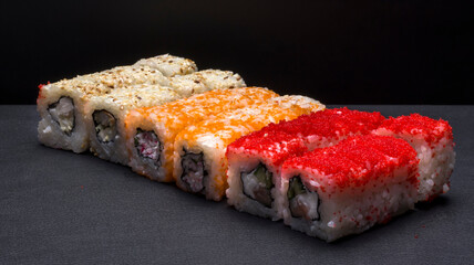 Japanese cuisine, rice rolls of different colors on a black background