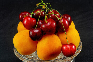 Fototapeta na wymiar Still life with apricot and cherry on a black background.