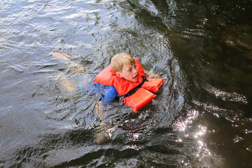 Kid Swimming in Lake Water Looking Distressed and Wearing a Life Vest