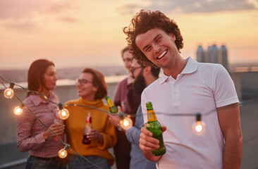 Fototapeta premium Cheerful man with beer during party with friends
