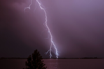 Fototapeta na wymiar Lightning strikes at night over a huge river