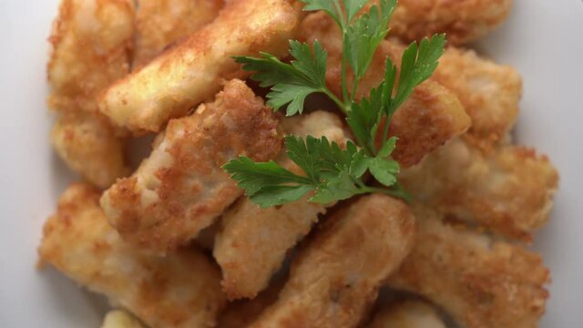Crispy fried cod fish fillet on a plate rotating in microwave close-up top view.
