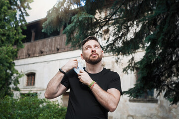 Handsome brutal young man removes face mask on the street. Happy end. Victory over coronavirus. Pandemic Covid-19. Coronavirus, COVID-19, 2019-nCoV concept.   