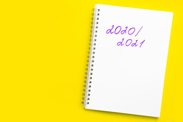 Inscription 2020 - 2021 in a white notebook with a spiral, on a yellow background. Concept of the new school year and return to school. Mockup with place for text.