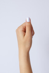 Gesture and sign, female hand holds something on a light background