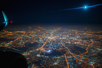 Aerial view to night city from the plane. Moon in the sky