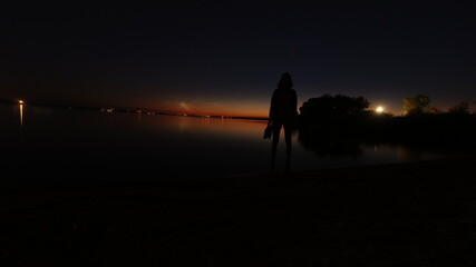 Silhouette of a man on the background of sunset and starry sky