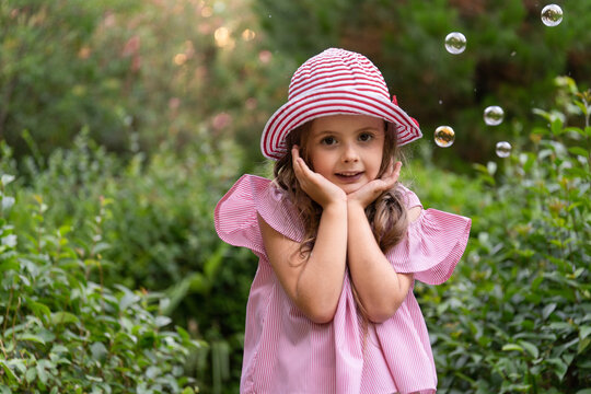 A little girl in fashionable clothes posing outdoors. Photo of a stylish five-year-old girl with soap bubbles