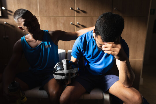 Two mixed race male football in changing room