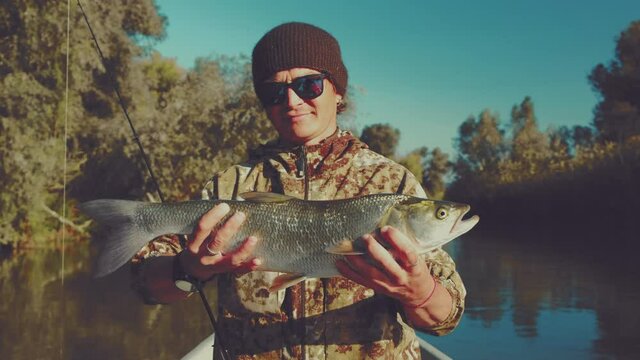 Angler with Asp fish. Young fisherman stands with Asp fish and shows it to the camera.
