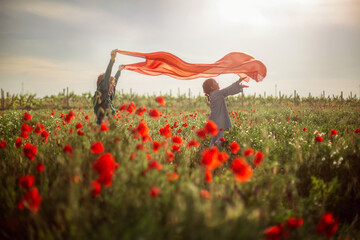 mom and daughter on a poppy field in the rays of the setting sun