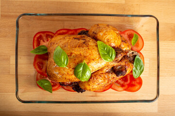 Roasted chicken. Golden brown skin, fresh basil leaves and sliced tomatoes.