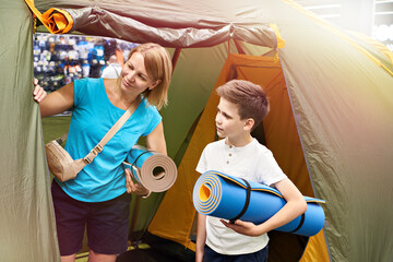 Mom and son choose a camping tent in the store