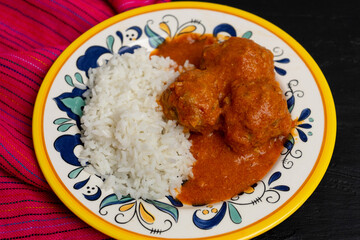 Mexican meatballs with chipotle sauce and rice on dark background