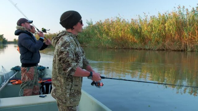 Anglers fishing from the boat floating on the river. Astrakhan region, Russia