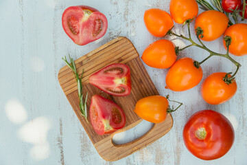Various colorful tomatoes and rosemary herb on a light blue background