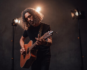 Talanted hispanic musician in black t-shirt playing guitar in stage lights