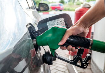  young woman refuels her car at a gas station