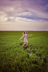Fototapeta na wymiar A girl runs across a green field in spring