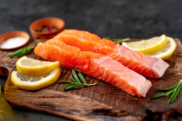 pieces of raw salmon with spices and lemon on a stone background