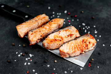 
grilled salmon slices over a meat knife on a stone background
