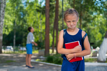 Unhappy girl with a book does not want to go to school. Mother sends daughter to first grade. The first day in elementary school.