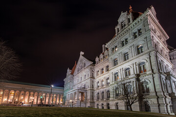 Fototapeta na wymiar North entrance to granite and red roof New York State Capitol building at night with state Education Department building in the background.