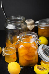 homemade organic apricot jam  and ripe apricots on black background