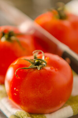 Tomaten mit Messer in Küche schneiden, Essen zubereiten und zu Hause kochen mit frischen Gemüse abgewaschen auf einem Trockentuch