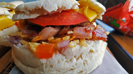 Delicioso sandwich con queso, tomate, panceta, papas y cebolla