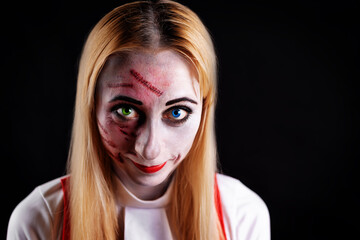 Fototapeta premium blond haired witch with green and blue eyes on a black background for Halloween