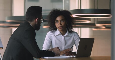 Female african manager broker advisor consulting arabic male client with laptop talking discussing bank loan deal benefits with arab customer collaborating convincing buy insurance services in office
