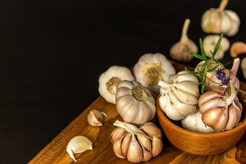 Garlic Cloves and Bulb in vintage wooden bowl.  Healthy food. Garlic on a wooden background. Traditional spices.