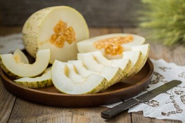 Ripe melon is cut on a dish on an old wooden table and an embroidered towel. Retro style, rustic