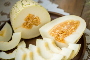 Ripe melon is cut on a dish on an old wooden table and an embroidered towel. Retro style, rustic